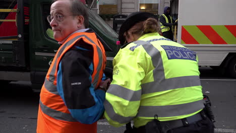 Una-Mujer-Policía-Escolta-A-Un-Anciano-Esposado-Y-Arrestado-Justo-Para-Detener-A-Un-Manifestante-Petrolero-En-La-Carretera-De-Whitehall