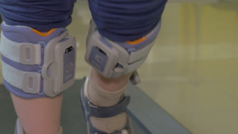 Close-up-view-of-boy-feet-on-treadmill-in-the-special-orthopedic-bandage-and-footwear-functional-electrical-stimulation-for-lower-limb