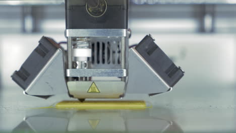 Front-close-up-view-of-3d-printer-in-process-It-makes-pieces-for-equipment-with-yellow-plastic
