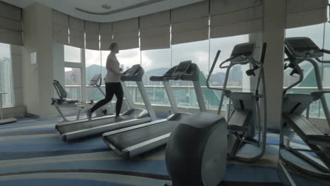 Woman-working-out-on-running-machine-and-looking-at-city