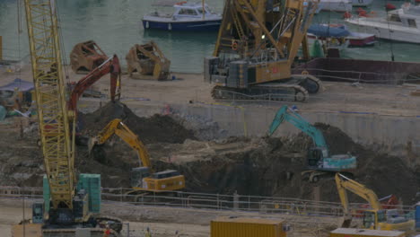 Vista-De-Excavadoras-Cavando-Un-Agujero-Cerca-Del-Muelle-De-Hong-Kong,-China