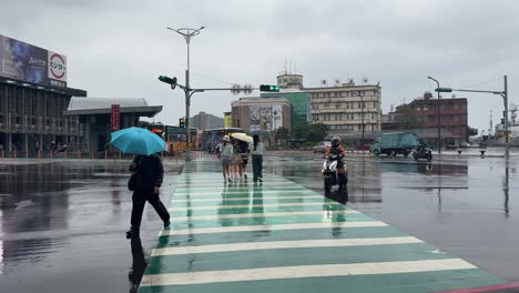 Rainy-city-street-view-and-people-crossing-the-street-in-Keelung-City,-Ren’ai-District,-Taiwan