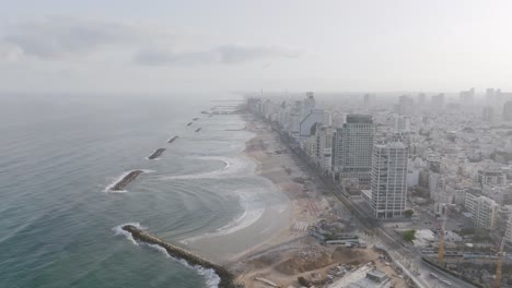 Static-aerial-wide-of-the-bays-and-beaches-of-hotels-in-Tel-Aviv,-Israel-in-the-hazy-light-of-the-morning-sun