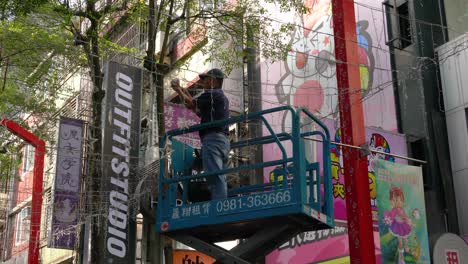Scene-of-worker-standing-on-the-mobile-elevated-work-platform-setting-up-Christmas-light-decorations-in-Taipei-Ximending,-Taiwan