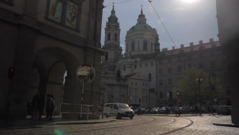 View-of-Saint-Nicholas-Church-Old-Town-Square-in-Prague-in-sun-day-and-road-with-cars-on-the-foreground-Czech-Republic