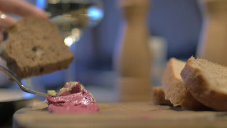 Close-up-view-of-meal-table-when-woman-hand-spreading-pate-on-wholegrain-bread