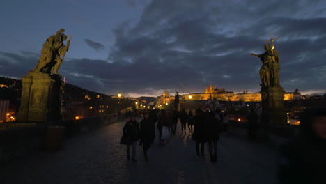 Tourists-walk-across-Charles-bridge-in-the-evening-in-Prague