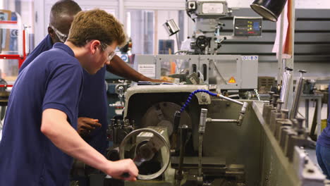 Engineer-Showing-Teenage-Apprentice-How-To-Use-Lathe