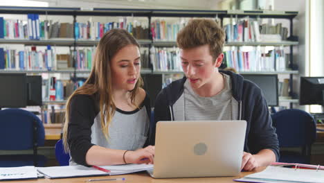 Male-And-Female-College-Students-Working-On-Laptop-In-Library