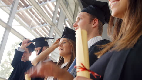 Students-At-Graduation-Ceremony-Throwing-Hats-In-The-Air