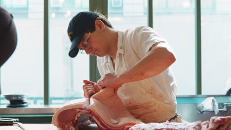Macho-Joven-Carnicero-Preparando-Cuidadosamente-Un-Gran-Corte-De-Carne