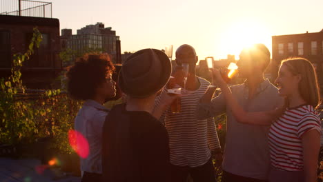 Young-adult-friends-making-a-toast-on-a-rooftop-at-sundown