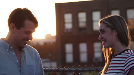 Young-white-couple-talking-on-a-Brooklyn-rooftop-at-sunset