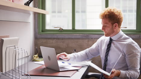 Red-haired-businessman-working-with-laptop-in-office,-close-up