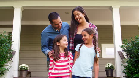 Portrait-Of-Smiling-Family-Standing-In-Front-Of-Their-Home