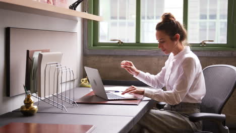 Mujer-Leyendo-Un-Documento-Y-Usando-Una-Computadora-Portátil-En-La-Oficina,-De-Cerca