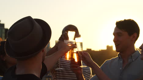 Friends-making-a-toast-on-a-rooftop-at-sundown,-close-up