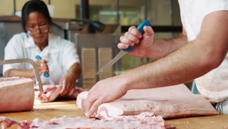 Bearded-butcher-cutting-meat-for-sale-at-a-butcher's-shop