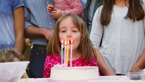Junges-Mädchen-Bläst-Kerzen-Bei-Ihrer-Geburtstags-Gartenparty-Aus