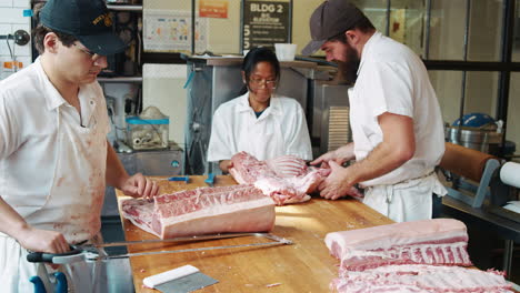 Three-butchers-preparing-meat-at-a-butcher's-shop