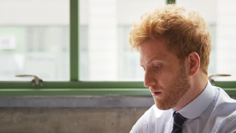 Red-haired-businessman-using-laptop,-head-and-shoulders