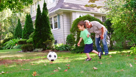 Grandfather-Playing-Soccer-In-Garden-With-Grandson