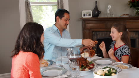 Jewish-man-sharing-challah-bread-with-family-at-Shabbat-meal