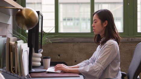 Junge-Asiatische-Frau-Mit-Computer-In-Einem-Büro,-Seitenansicht,