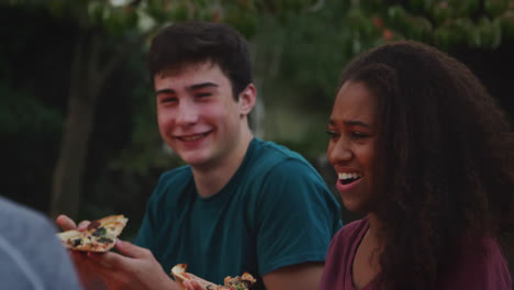 Teenager-Freunde-Sitzen-Um-Eine-Feuerstelle-Und-Essen-Pizza-Zum-Mitnehmen