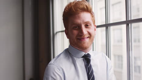 Red-haired-businessman-turns-and-smiles-to-camera,-close-up