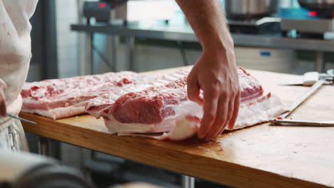 Mid-section-of-butchers-preparing-cuts-of-meat