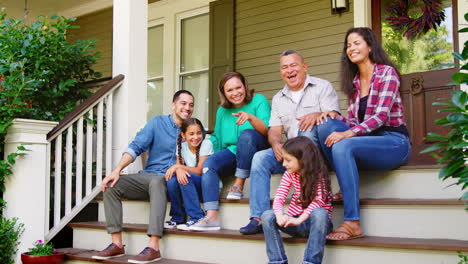Mehrgenerationenfamilien-Sitzen-Auf-Stufen,-Die-Zur-Veranda-Des-Hauses-Führen