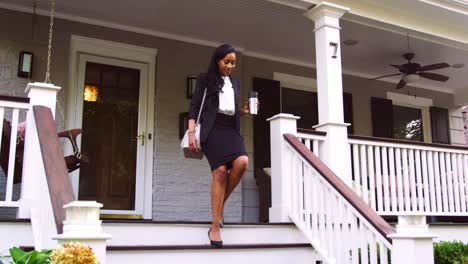 Businesswoman-With-Cup-Of-Coffee-Leaving-Suburban-House-For-Work