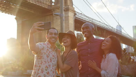 Group-Of-Friends-Posing-For-Selfie-In-Front-Of-Brooklyn-Bridge