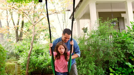 Father-Pushing-Daughter-On-Garden-Swing-At-Home