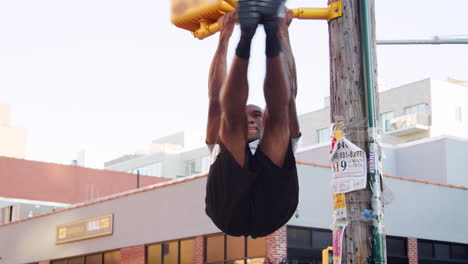 Young-black-man-doing-pull-ups-from-crossing-light-in-street
