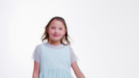 Girl-Walks-Into-Focus-And-Poses-Against-White-Studio-Background