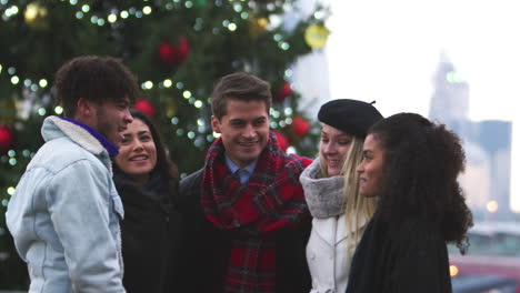 Friends-Stand-In-Front-Of-Christmas-Tree-On-South-Bank-In-London