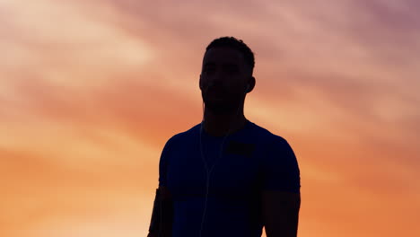 Silhouette-of-male-athlete-crossing-arms-at-sunset,-waist-up