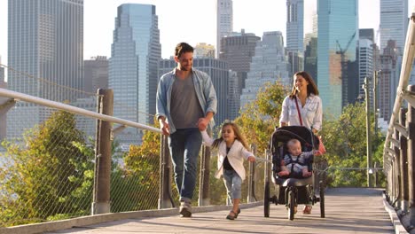 Familia-Joven-Caminando-Con-Un-Cochecito-En-El-Puente-Peatonal,-Manhattan