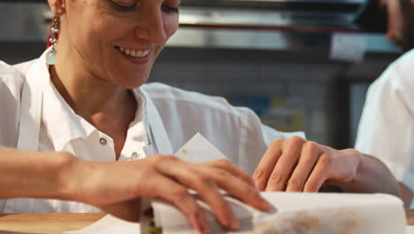 Young-woman-wrapping-food-for-take-away-at-a-deli,cafe,-close-up