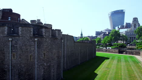 LONDON---MAY,-2017:-Exterior-wall-and-lawn-at-the-Tower-of-London-with-modern-buildings-in-the-background,-City-of-London,-London,-EC2
