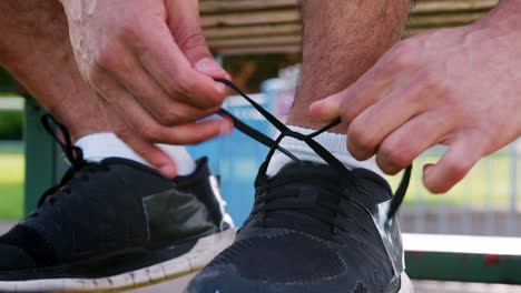 Male-runner-tying-shoelaces-outdoors,-low-section,-detail