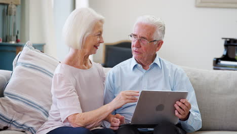 Älteres-Paar-Sitzt-Zusammen-Auf-Dem-Sofa-Und-Benutzt-Laptop-Zu-Hause