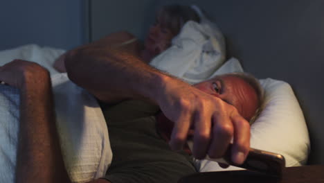 Schlafloser-älterer-Mann,-Der-Nachts-Im-Bett-Liegt-Und-Sein-Mobiltelefon-Benutzt