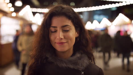 Portrait-Of-Smiling-Woman-Enjoying-Christmas-Market-At-Night