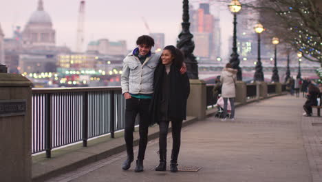 Couple-Walking-Along-South-Bank-On-Winter-Visit-To-London