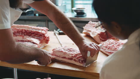 Carnicero-Mostrando-A-Un-Colega-Cómo-Pelar-Un-Corte-De-Carne