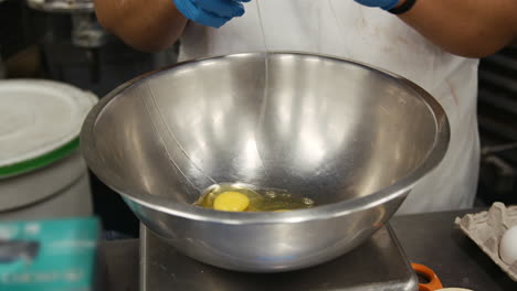 Baker-breaking-eggs-into-a-mixing-bowl,-mid-section