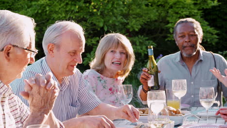 Eine-Gruppe-älterer-Freunde-Genießt-Eine-Dinnerparty-Im-Freien-Zu-Hause